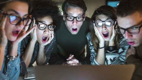 Group of shocked-looking people looking at computer screen.